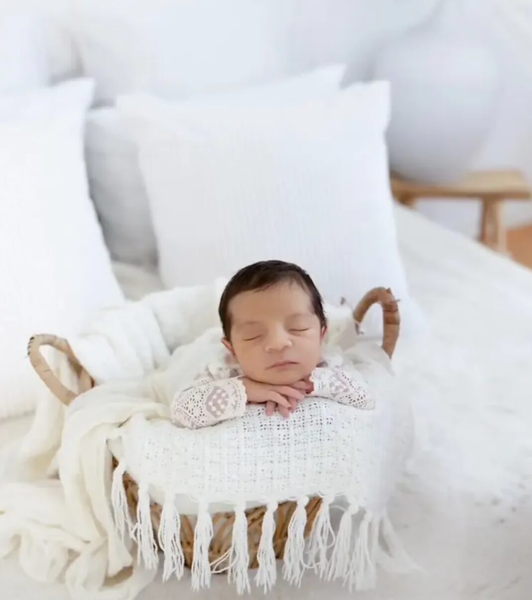 Neugeborenenshooting – Baby schläft im Körbchen auf weißem Bett